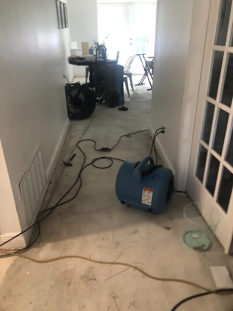 Air mover drying hallway flooring after a leak