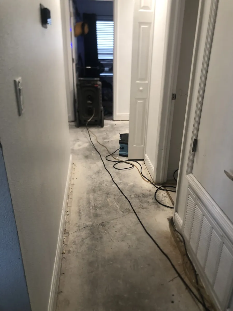 Dehumidifier and air mover drying a hallway after a water leak
