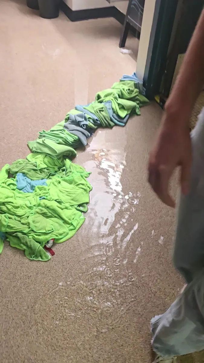 Standing water across a tile floor with towels laid down to soak it up