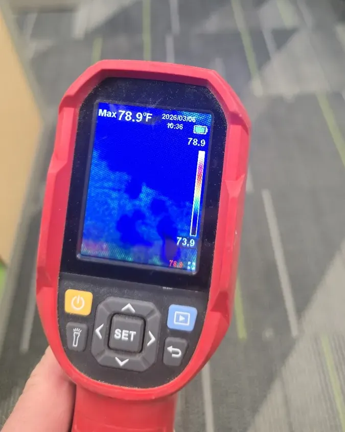 Thermal camera screen showing cooler, damp areas in a carpeted floor during a moisture check