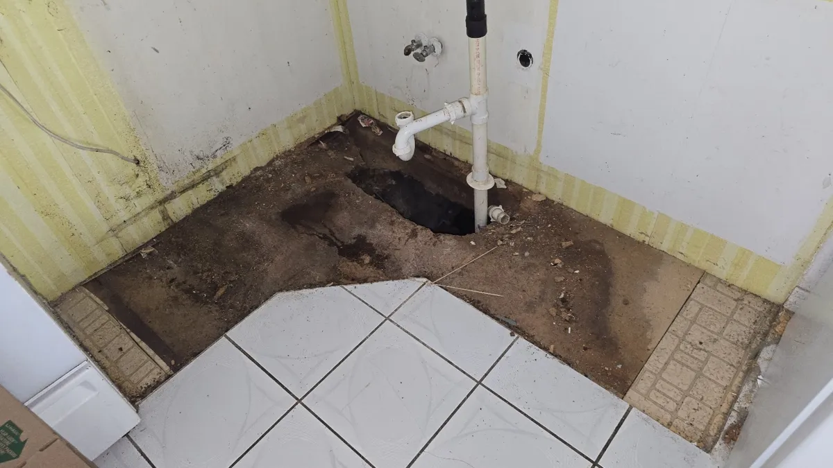 Bathroom floor opened up to show water-damaged subfloor under the tile